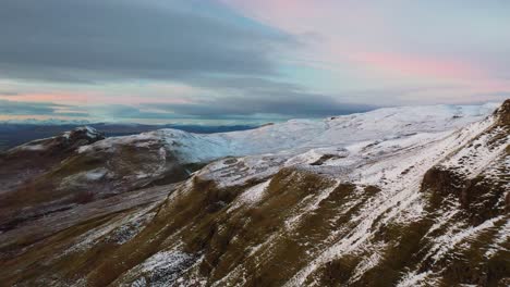 4K-Drone-shot-of-Campsie-Fells-cliffs-at-sunset-panning-to-reveal-Dumgoyne-Hill,-above-Glengoyne