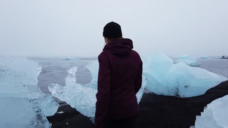 Follow-shot-of-Tourist-walking-through-icebergs-on-Diamond-Beach-in-South-Iceland