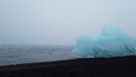Turista-Caminando-En-La-Playa-De-Arena-Negra-Con-Icebergs---Breidamerkursandur-También-Conocida-Como-Playa-De-Diamantes-En-El-Sur-De-Islandia