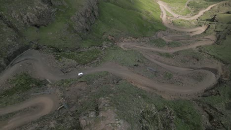 Aerial-rotates-to-reveal-harsh-switchback-descent-at-Sani-Pass,-ZA