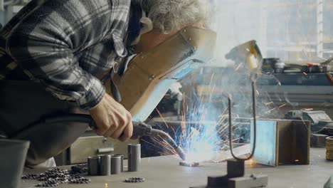 Shot-Of-Blacksmith-Welding-In-Workshop,-Sparks-Flying-In-Air