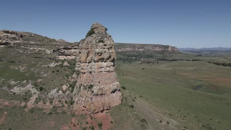 Prominent-rock-cliff-face-towers-over-surrounding-green-mountain-plateau