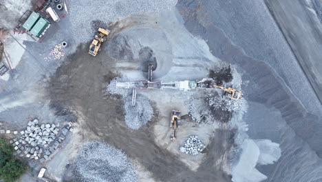 Drone-shot-of-conveyer-belt-and-bob-cat-sorting-rocks-and-rubble-into-piles-in-quarry-mine