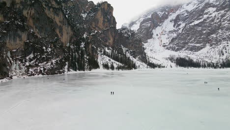 Drone-Flying-Over-Frozen-Lake-Braies-In-Trentino-With-People-Walking-On-Cold-Winter-Day