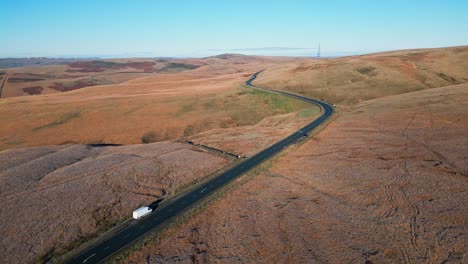 Distant-car-driving-down-a-country-road-in-the-moors-of-the-UK-with-barron-landscape