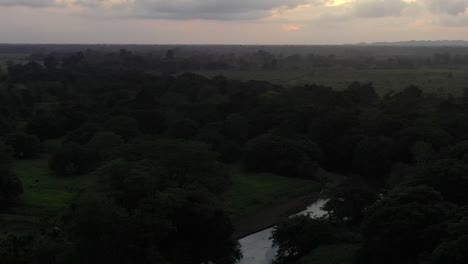 River-and-forest-area-in-the-outskirts-of-San-Jose,-Costa-Rica-with-cattle-grazing,-Aerial-pan-left-shot