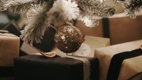Konzentrieren-Sie-Sich-Von-Einem-Geschenk-Unter-Einem-Weihnachtsbaum-Auf-Ein-Einzelnes-Glänzendes-Goldornament,-Das-Am-Baum-Hängt