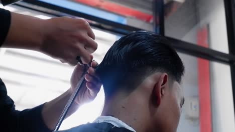 Close-up-of-barber-cuts-the-hair-by-scissors-at-barbershop