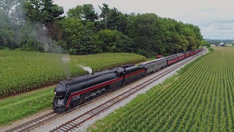 A-Drone-View-of-an-Antique-Restored-Steam-Engine-and-Passenger-Coaches-getting-Ready-to-Leave-a-Small-Train-Station-on-a-Summer-Day