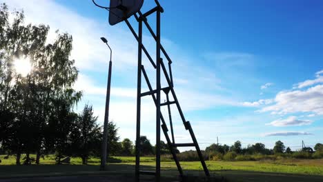 Silhouette-of-vintage-basketball-board-in-rural-area,-tilt-up-view