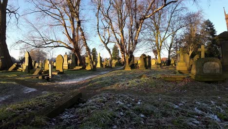 FPV-flying-around-headstones-in-snowy-autumn-sunrise-golden-hour-churchyard-cemetery