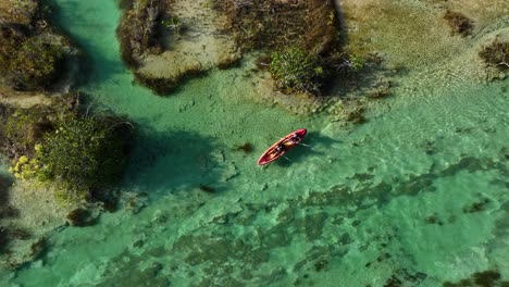 Aerial-view-above-a-canoe-in-the-Bacalar-rapids,-in-sunny-Mexico---top-down,-drone-shot