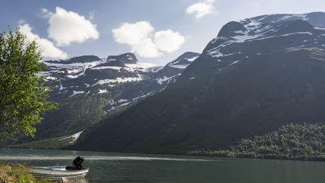 Boot,-Das-Im-Winter-Am-Seeufer-Am-Fjord-Festgemacht-Ist,-Mit-Felsigem-Berg-Im-Hintergrund---Bewegungszeitraffer
