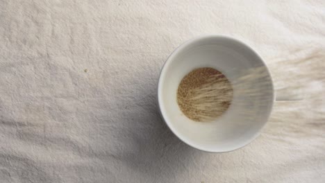 Raw-brown-sugar-in-white-ceramic-tableware-on-white-mat