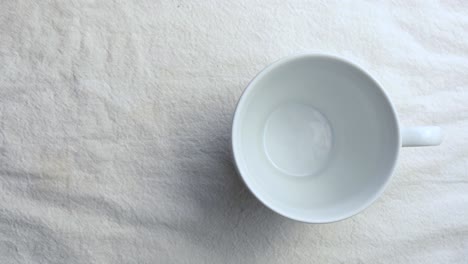 White-ceramic-tableware-cup-on-white-table-mat