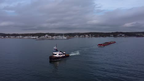 Aerial:-Circling-tugboat-pulling-cargo
