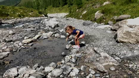 Cute-little-girl-having-fun-trying-the-water-of-a-mountain-river