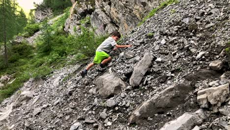 Cute-young-boy-slipping-while-climbing-mountain-full-of-rubble