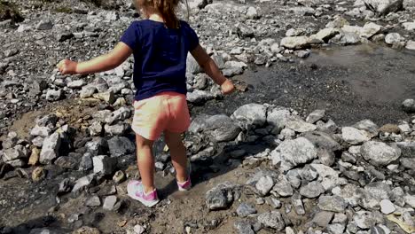Cute-little-girl-having-fun-trying-the-water-of-a-mountain-river