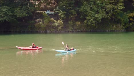 Slide-shot-of-people-kayaking-down-a-river-in-Kyoto,-Japan-4K-slow-motion