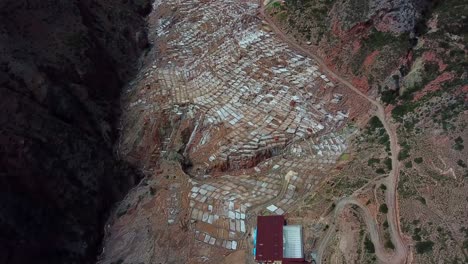 Aerial,-drone-shot-overlooking-a-salt-mine,-Salineras,-in-the-Andes-mountains,-on-a-cloudy-day,-in-Peru,-South-America