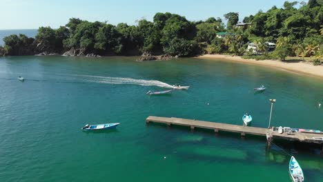 Vista-Aérea-De-Un-Barco-De-Pesca-Que-Regresa-De-Un-Viaje-De-Pesca-Al-Pueblo-De-Parlatuvier,-Tobago