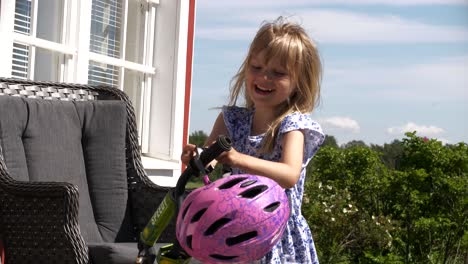 Glücklich-Lächelndes-Kleines-Mädchen-Nimmt-Helm,-Um-Fahrrad-Zu-Fahren