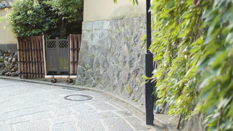 City-street-corner-with-green-leaves-hanging-off-the-stone-walls-in-Kyoto,-Japan-soft-lighting