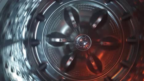 Stainless-steel-washing-machine-drum-turning-spin-cycle,-futuristic-industrial-look-of-modern-machinery
