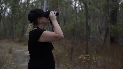 Blonde-girl-wearing-hat-looking-through-binoculars-in-nature
