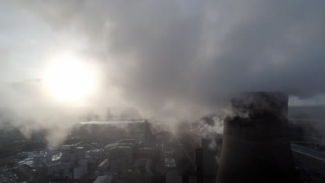 Aerial-pull-back-reveal-of-UK-power-station-cooling-towers-through-atmospheric-steam-emissions-at-sunrise