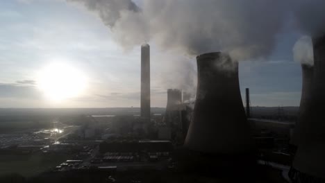 Aerial-push-in-towards-UK-power-station-cooling-towers-under-pollution-steam-emissions-at-sunrise