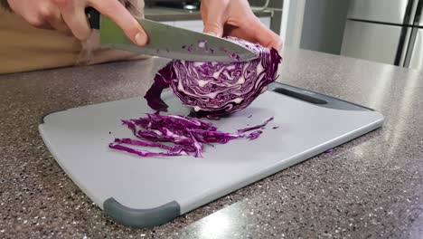 Cropped-view-of-a-man-slicing-red-cabbage-in-a-kitchen-with-a-big-knife