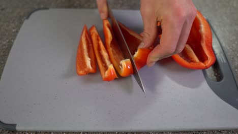 Küchenbrett-Mit-Rotem-Paprika,-Der-In-Kleine-Stücke-Geschnitten-Wird