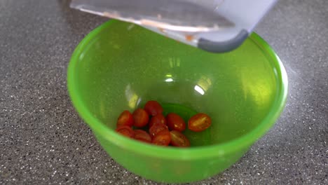 Making-salad-with-tomatoes,-Throwing-cherry-tomatoes-into-a-green-bowl