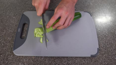 Man-Slicing-cucumber-on-kitchen-chopping-board