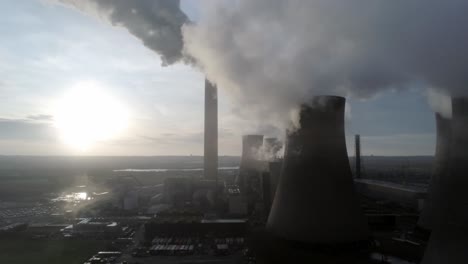 Aerial-descending-down-UK-power-station-cooling-towers-smoke-steam-emissions-at-sunrise