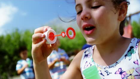 Close-up-of-schoolgirl-playing-with-bubble-wand-in-playground