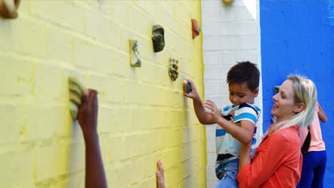 Trainer-assisting-kids-in-climbing-wall