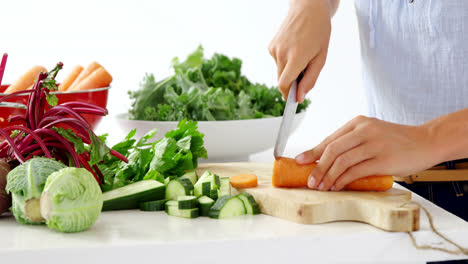 Mid-section-of-woman-cutting-vegetables-on-chopping-board