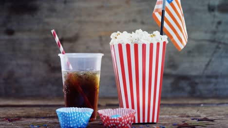 Popcorn,-confectionery-and-drink-on-wooden-table