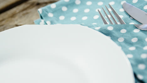 White-plate-with-cutlery-and-napkin-on-table