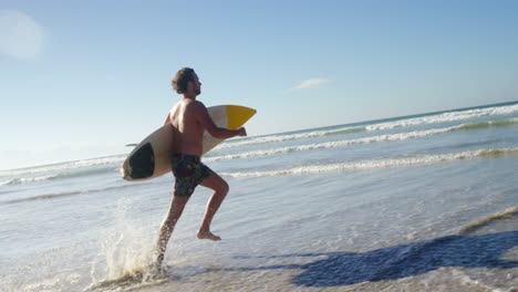 Man-running-with-surfboard-at-beach