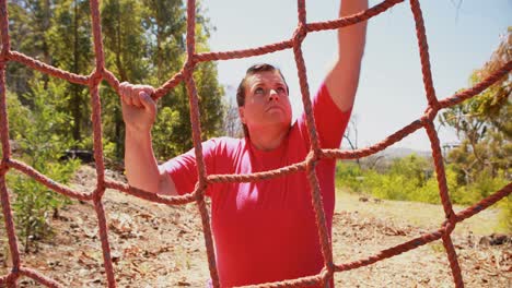 Determined-woman-climbing-a-net-during-obstacle-course