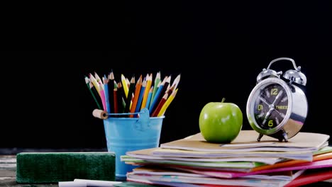 Apple-and-alarm-clock-on-book-stack-with-school-supplies