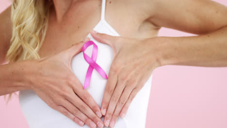 Mid-section-of-woman-showing-breast-cancer-awareness-ribbon