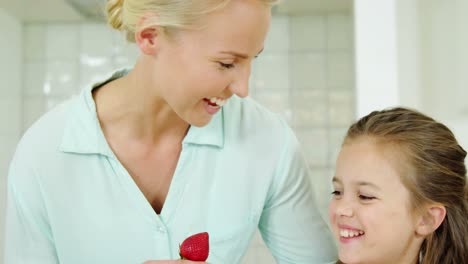 Smiling-daughter-giving-strawberry-to-her-mother