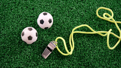 Footballs-and-referee-whistle-on-artificial-grass-4k