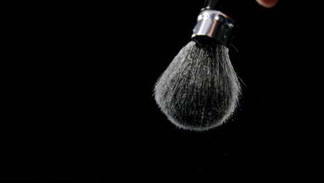 Person-hand-splashing-water-from-shaving-brush-against-black-background-4k