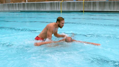 Lifeguard-rescuing-senior-man-from-swimming-pool